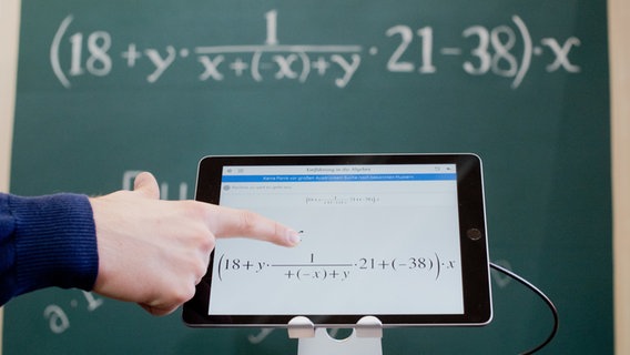Ein Tablet mit einer mathematischen Formel vor einer Kreidetafel mit der gleichen Formel. © picture alliance/dpa Foto: Julian Stratenschulte