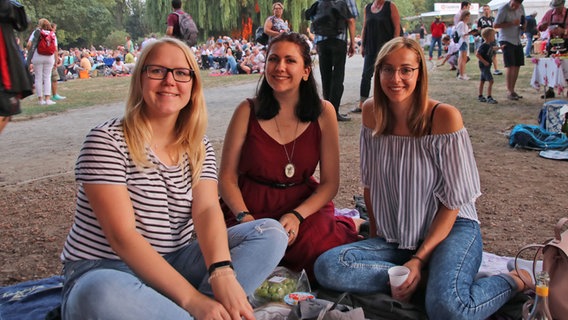 Drei junge Frauen sitzen beim NDR Klassik Open Air 2018 (Generalprobe) im Maschpark. © NDR Foto: Julia Scheper