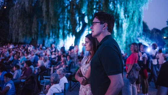 Besucher des NDR Klassik Open Air 2018 (Generalprobe) sitzen in lila Licht auf dem Boden. © NDR Foto: Julius Matuschik