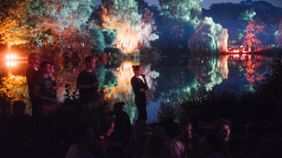 Zuschauer beim NDR Klassik Open Air 2018 (Generalprobe) vor bunt beleuchteten Bäumen im Maschpark. © NDR Foto: Julius Matuschik