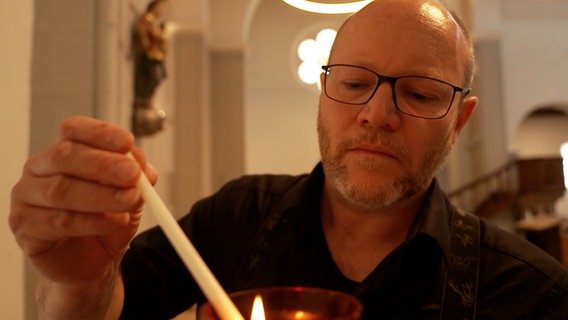 Pfarrer matthias Eggers zündet eine Kerze an. © NDR 
