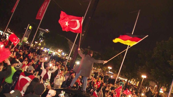 Ein Mann schwenkt gleichzeitig die türkische und die deutsche Fahne. Zahlreiche Fans der türkischen Nationalmannschaft feiern in Hannover den Einzug ins Viertelfinale. © Hannover Reporter 