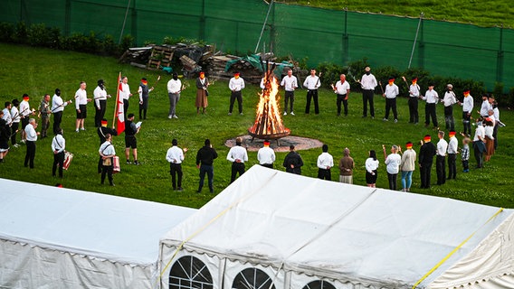 Menschen stehen in Eschede im Landkreis Celle mit Fackeln und Trommeln in einem Kreis um eine brennende Rune aus Holz. © Recherche Nord 
