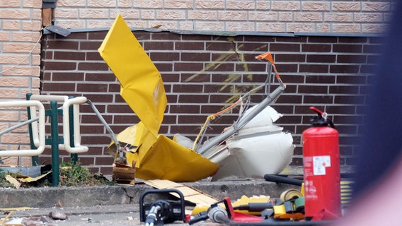 Die Trümmer eines Sportflugzeugs liegen an den Mauern eines teilweise beschädigten Hauses. © picture alliance Foto: Christian Gossmann