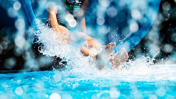 Ein Mädchen rutscht in einem Freibad von einer Riesenrutsche ins Wasser. © dpa-Bildfunk Foto: Swen Pförtner