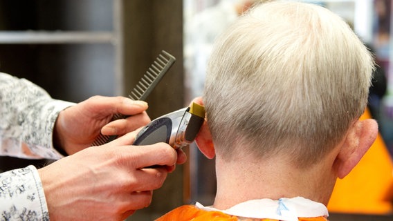 Ein Friseur schneidet einem Kunden die Haare. © dpa 
