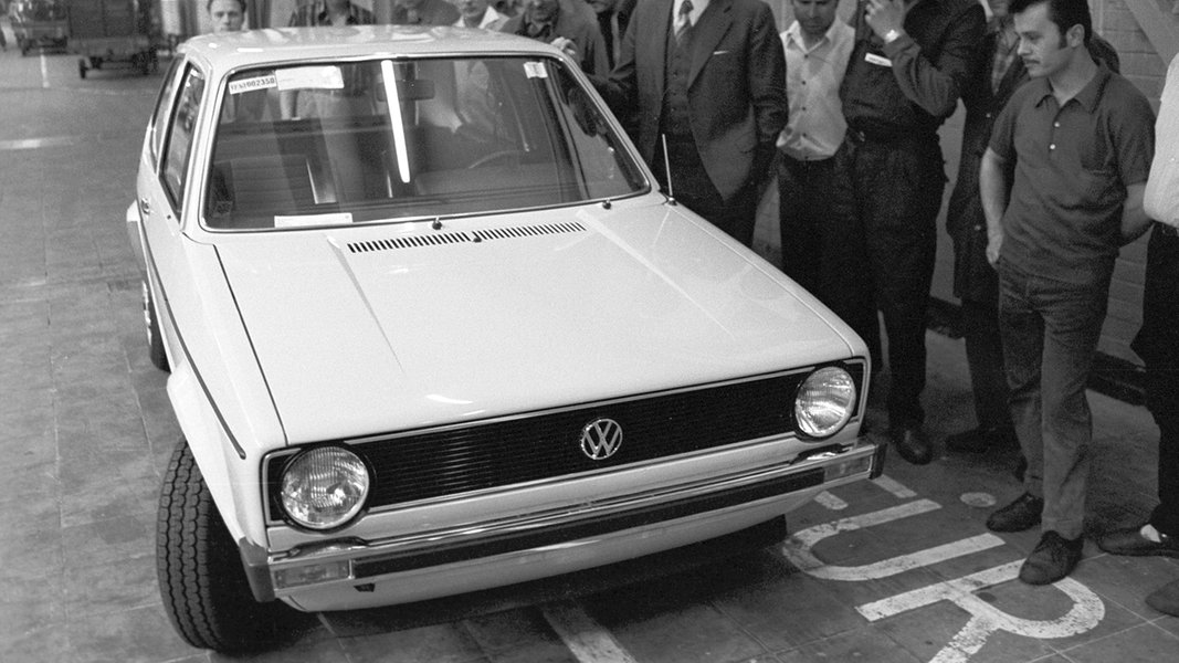 Mehrere Personen inspizieren 1974 den neuen VW Golf.