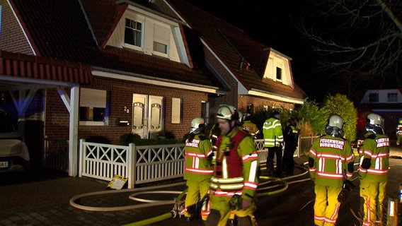 Einsatzkräfte der Feuerwehr stehen vor einem Haus. © NonstopNews 