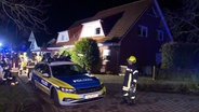 Einsatzkräfte der Feuerwehr stehen vor einem Haus. © NonstopNews 