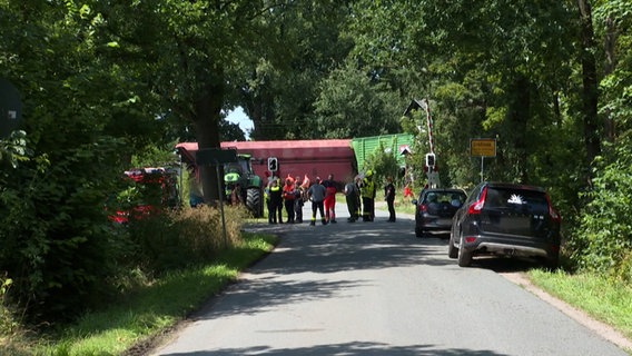Nach einem Unfall an einem Bahnübergang im Landkreis Celle stehen ein Güterzug und ein Anhänger auf bzw. an den Gleisen. © HannoverReporter 