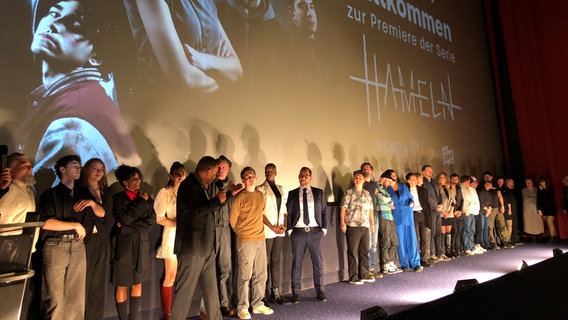 Schauspieler stehen vor einer Kinoleinwand bei der Premiere der Horrorserie "HAMELN". © NDR Foto: Wilhelm Purk