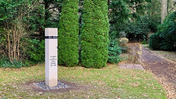 Eine Stele aus Sandstein steht auf einem Friedhof zum Gedenken an die Verstorbenen der Corona-Pandemie. © Stadt Hameln 