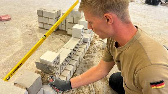 Der Maurer Thomas Block schichtet Steine aufeinander. © NDR Foto: Svenja Nanninga