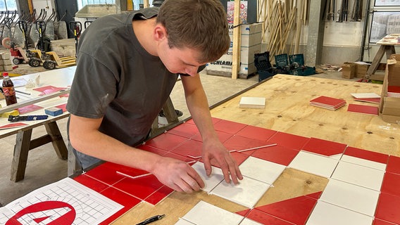 Der Fliesenleger Sven Kirchhoff arbeitet an einem Tisch. © NDR Foto: Svenja Nanninga