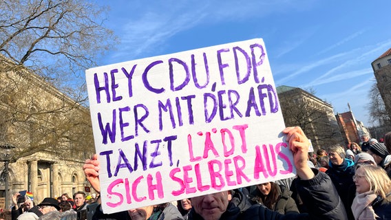 Ein Mann hält ein Schild mit der Aufschrift "Hey CDU, FDP. Wer mit der AfD tanzt, lädt sich selber aus" in den Händen. © NDR Foto: Christina Herz