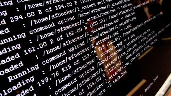 Ein illustrativen Hackerangriff (weiße Zeichen auf schwarzem Bildschirm) auf der Hannover Messe 2018 am Stand von Trend Micro. © dpa-Bildfunk Foto: Julian Stratenschulte