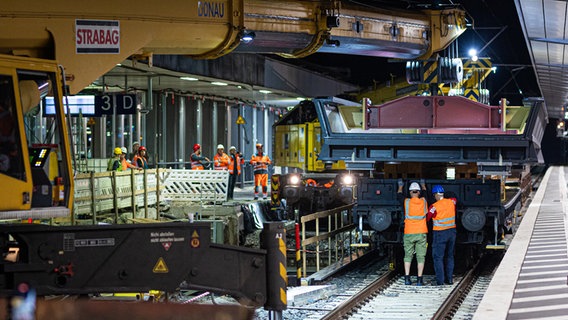 Zwei Schienenkräne heben in der Nacht einen Stahl-Trog von einem Güterwaggon im Hauptbahnhof Hannover. © Moritz Frankenberg/dpa Foto: Moritz Frankenberg/dpa