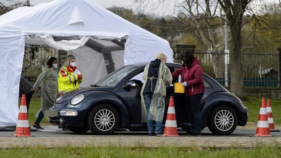 Impfhelfer stehen um einen Pkw in einem Drive-In Impfzentrum. © dpa-Bildfunk Foto: Swen Pförtner