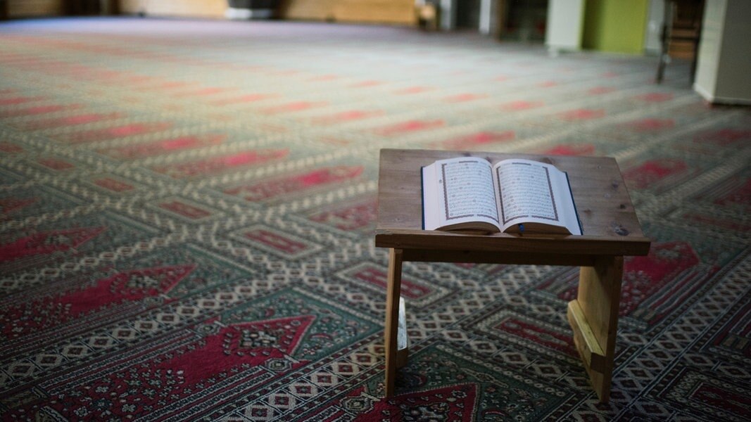 Ein Koran auf Koranständer und einem Gebetsteppich in einer Moschee.