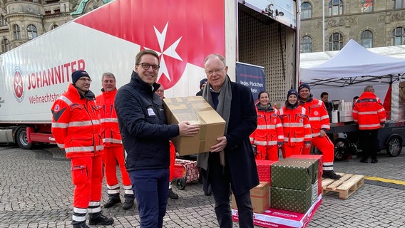 Stephan Weil (SPD) posiert mit einem Paket in der Hand bei einem Pressetermin der Johanniter Weihnachtsaktion. © NDR Foto: Vera Zellmer