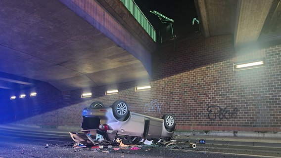 Ein Auto liegt in Lehrte-Hämelerwald unterhalb einer Brücke auf dem Dach und ist stark beschädigt. © Freiwillige Feuerwehr Lehrte/dpa Foto: Freiwillige Feuerwehr Lehrte/dpa