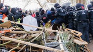 Polizisten drängen Demonstranten zurück, die einen Zufahrtsweg blockiert hatten. Die Polizei will das Protestcamp "Tümpeltown" am Südschnellweg Hannover räumen. © Sarah Knorr/dpa Foto: Sarah Knorr/dpa