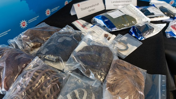 Sichergestellte Perücken und andere Hilfsmittel zur Verschleierung der Identität liegen auf einem Tisch. © Landeskriminalamt Niedersachsen 