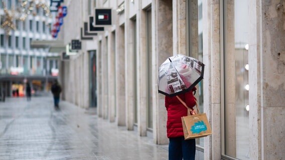 A passer-by looks into the window of a closed shop in the deserted city center of Hanover.  © picture alliance / dpa Photo: Julian Stratenschulte