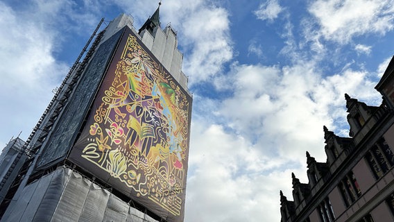 Ein Baugerüst an der Marktkirche ist einem großflächigen Bild des Künstlers Sebastian Peetz geschmückt. © NDR Foto: Kristina Hoffmann