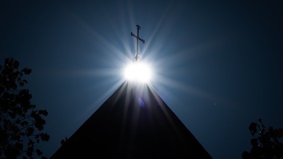 Die Sonne strahlt unter einem Kreuz. © picture alliance/dpa | Friso Gentsch Foto: Friso Gentsch