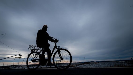 Ein Mann fährt in Mardorf am Steinhuder Meer bei bedecktem Himmel auf einem Fahrrad. © dpa-bildfunk Foto: Peter Steffen