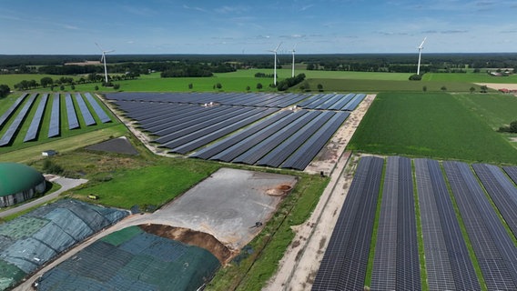 Eine Drohnenaufnahme zeigt einen Solarpark neben einer Papierfabrik. © NDR 