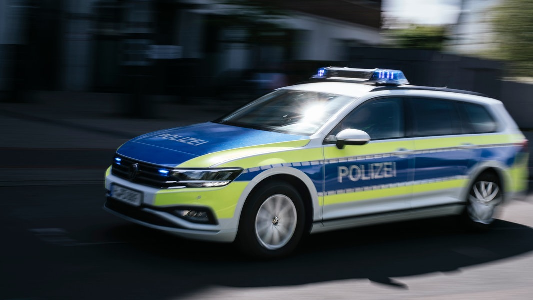 Ein Polizeiauto in Unschärfe fährt mit Blaulicht eine Straße in Hannover entlang.