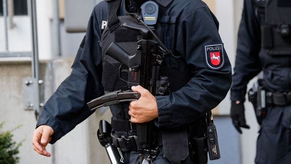 Ein schwer bewaffneter Polizist mit Maschinenpistole und kugelsicherer Weste. © picture alliance/dpa Foto: Julian Stratenschulte