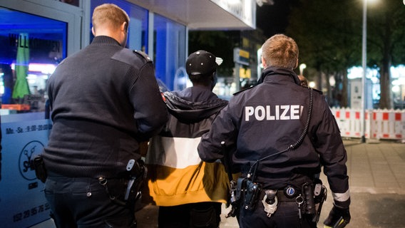 Polizisten nehmen einen Mann nach einer Drogen-Kontrolle in einem Wettbüro fest. © picture alliance/dpa Foto: Julian Stratenschulte/dpa