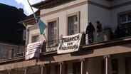 Eine Gruppe steht auf einem Balkon, an dem mehrere Transparente angebracht sind. © HannoverReporter 