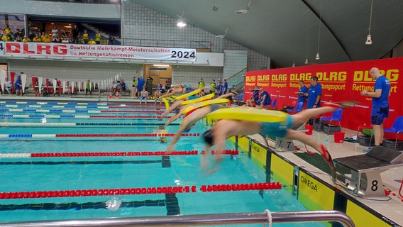 Schwimmer springen bei den Rettungsschwimmer-Meisterschaften ins Becken. © NDR Foto: Svenja Estner