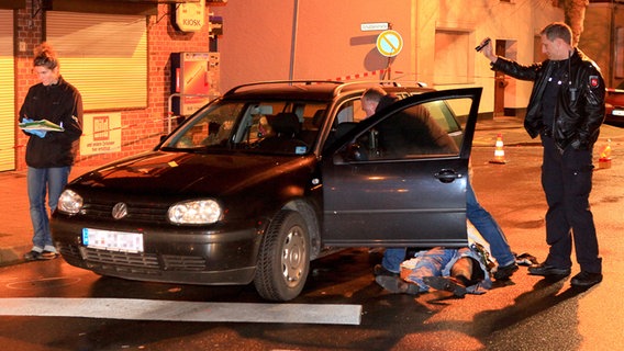 Die Leiche eines erschossenen Mannes liegt neben einem Fahrzeug in Sarstedt. © dpa Foto: Christian Elsner