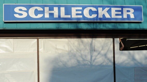 Eine Mitarbeiterin der Drogeriekette Schlecker klebt Geschenkpapier aus dem Schlecker-Sortiment an die Schaufenster einer Filiale in Hannover. © dpa-Bildfunk Foto: Julian Stratenschulte