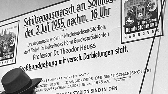 Ein Mann mit Hut betrachtet ein historisches Plakat vom Schützenausmarsch am 3. Juli 1955 in Hannover. © HAZ-Hauschild-Archiv, Historisches Museum Hannover 