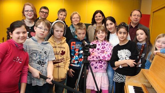 Eine Gruppe Kinder positionieren sich hinter einer Kamera. © NDR Foto: Eric Klitzke