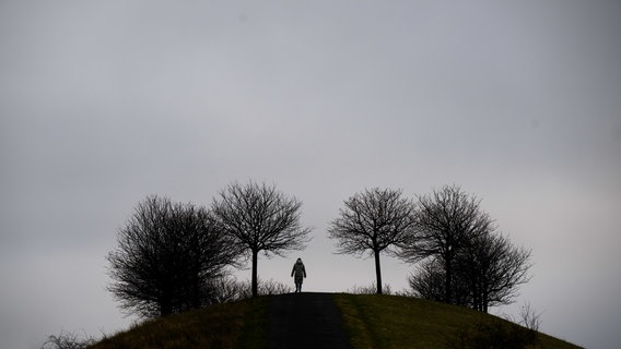 Hannover: Eine Frau spaziert vor grauen Himmel am Kronsberg. © dpa-Bildfunk Foto: Julian Stratenschulte