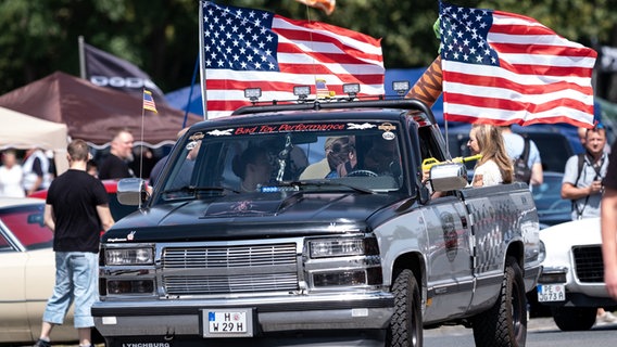 Besucher fahren mit ihrem Pickup mit US-Flaggen während der Street Mag Show in Hannover über das Gelände. © dpa-Bildfunk Foto: Peter Steffen