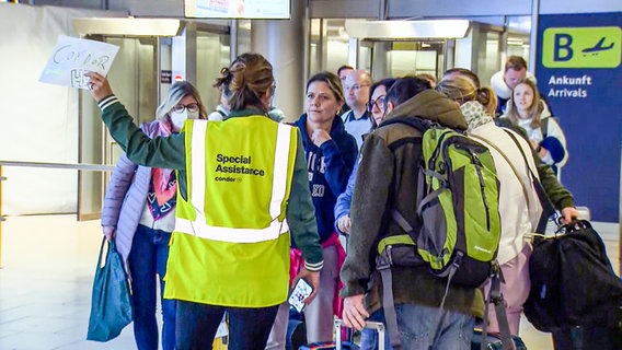 Passagiere, die wegen eines Streiks von Hamburg nach Hannover umgeleitet wurden, sprechen mit einer Angestellten des Flughafens. © NonstopNews 