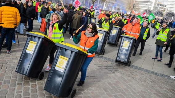 Beschäftigte des kommunalen Abfallentsorgers aha Zweckverband Abfallwirtschaft Region Hannover kommen mit zu Trommeln umfunktionierten Mülltonnen zu einer Streikkundgebung von Beschäftigten des öffentlichen Dienstes auf dem Opernplatz. © dpa Foto: Julian Stratenschulte