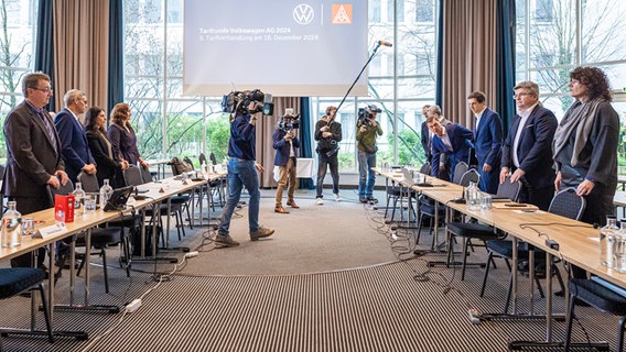 Die Vertreter von Volkswagen und IG Metall, stehen vor Beginn der fünften Tarifverhandlung von Volkswagen und IG Metall an ihren Plätzen. © dpa Foto: Moritz Frankenberg