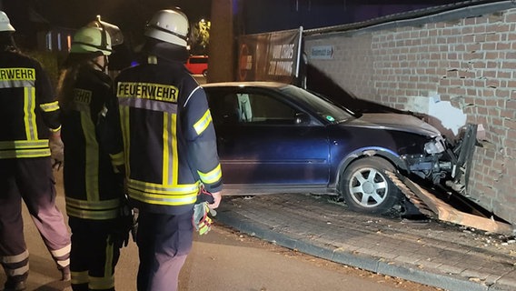 Drei Feuerwehrleute betrachten ein Auto, das gegen eine Backsteinwand gefahren ist. © Feuerwehr Celle Foto: Feuerwehr Celle