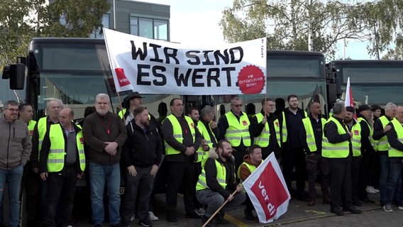 Beschäftigte des Verkehrsunternehmens Regiobus stehen mit Warnwesten der Gewerkschaft Verdi und einem Transparent mit der Aufschrift «Wir sind es wert» am Busdepot. © Frm/dpa +++ dpa-Bildfunk 