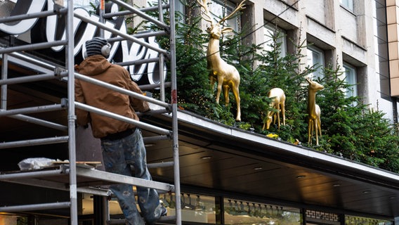 Ein Arbeiter dekoriert die Fassade eines Geschäftshauses in Hannover weihnachtlich. © dpa Foto: Alicia Windzio