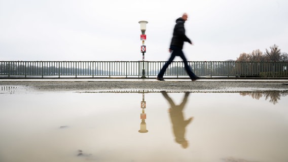 Ein Spaziergänger läuft über eine Brücke in Hannover. © Julian Stratenschulte/dpa Foto: Julian Stratenschulte